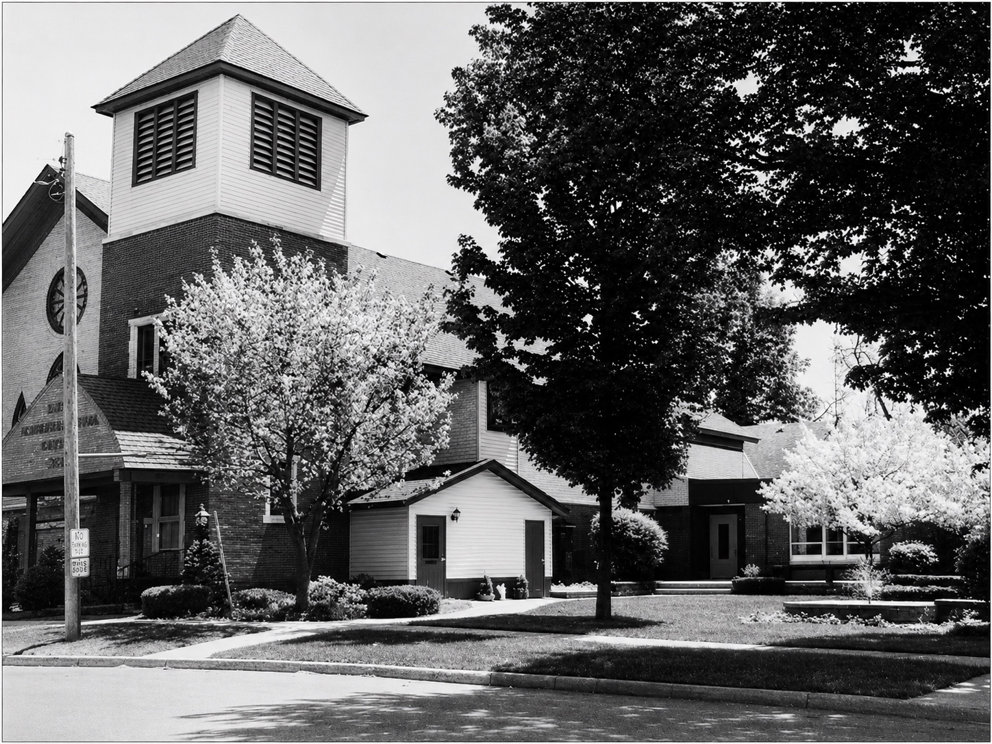A church building framed by mature and flowering trees