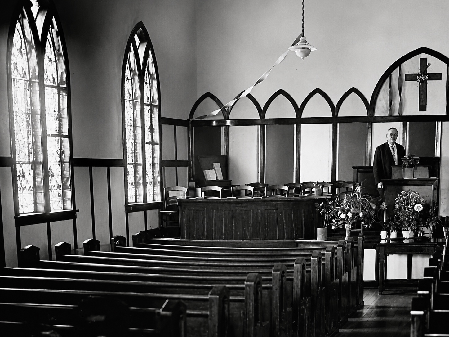 A historic sanctuary with pews, Gothic windows, and pulpit